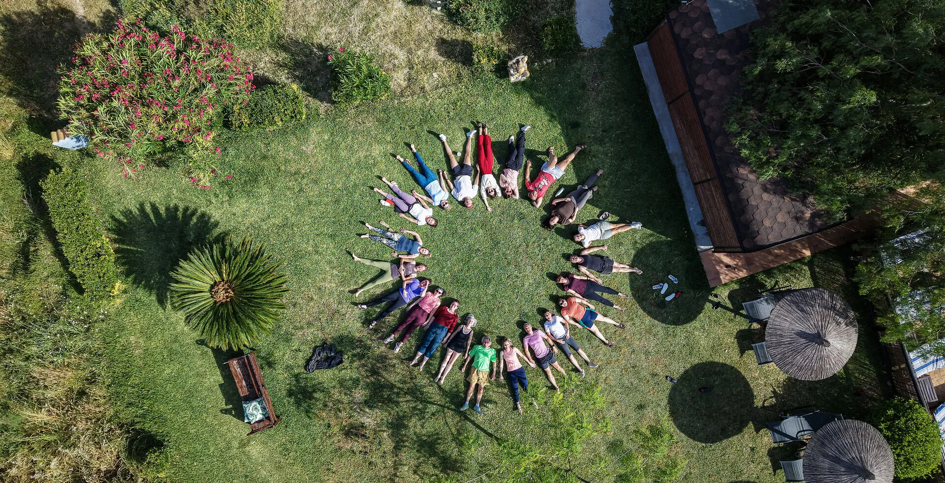 Aerial view of a retreat group lying in a circle on the lawn at Suryalila