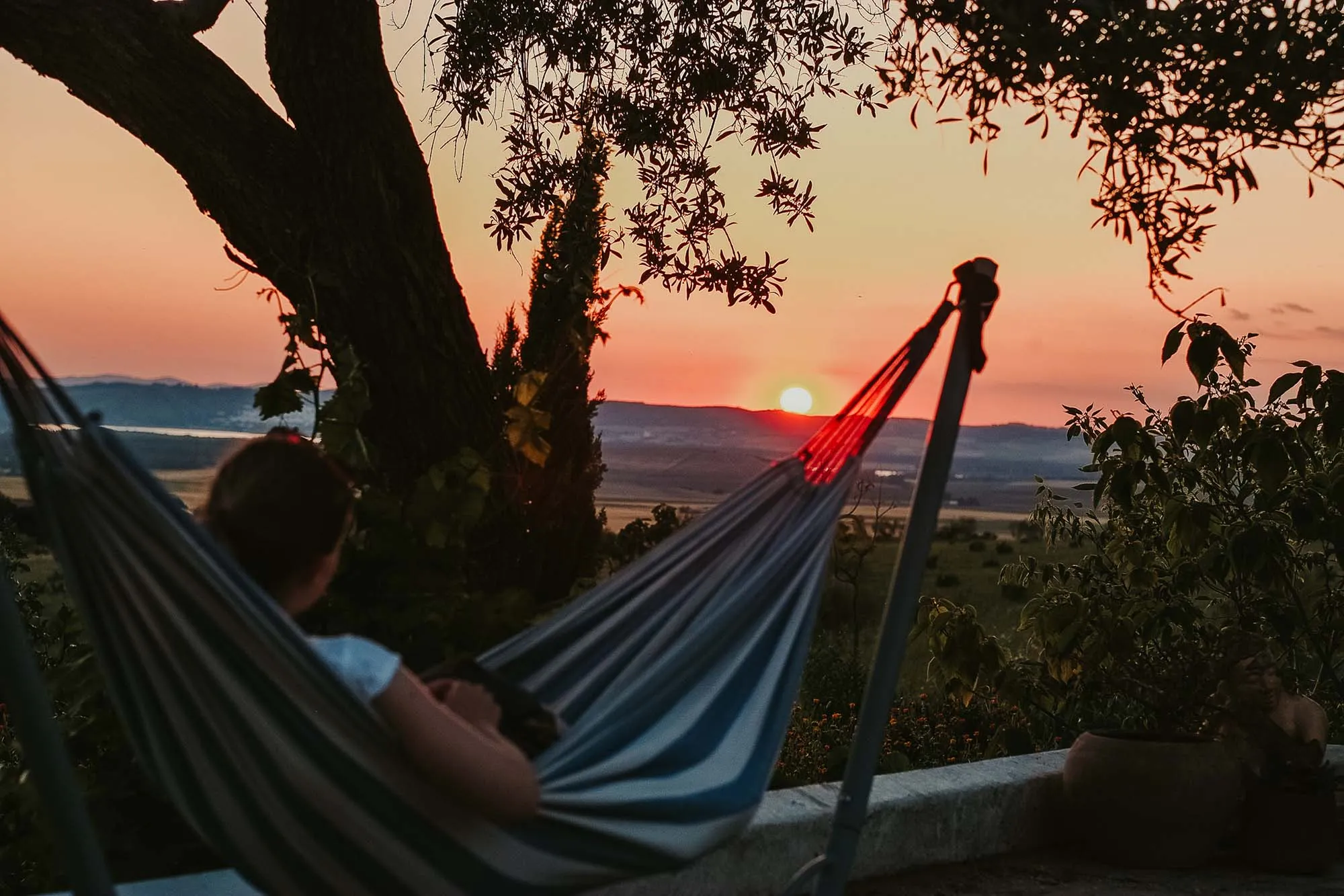 Reading a book in a hammock while the sun is setting