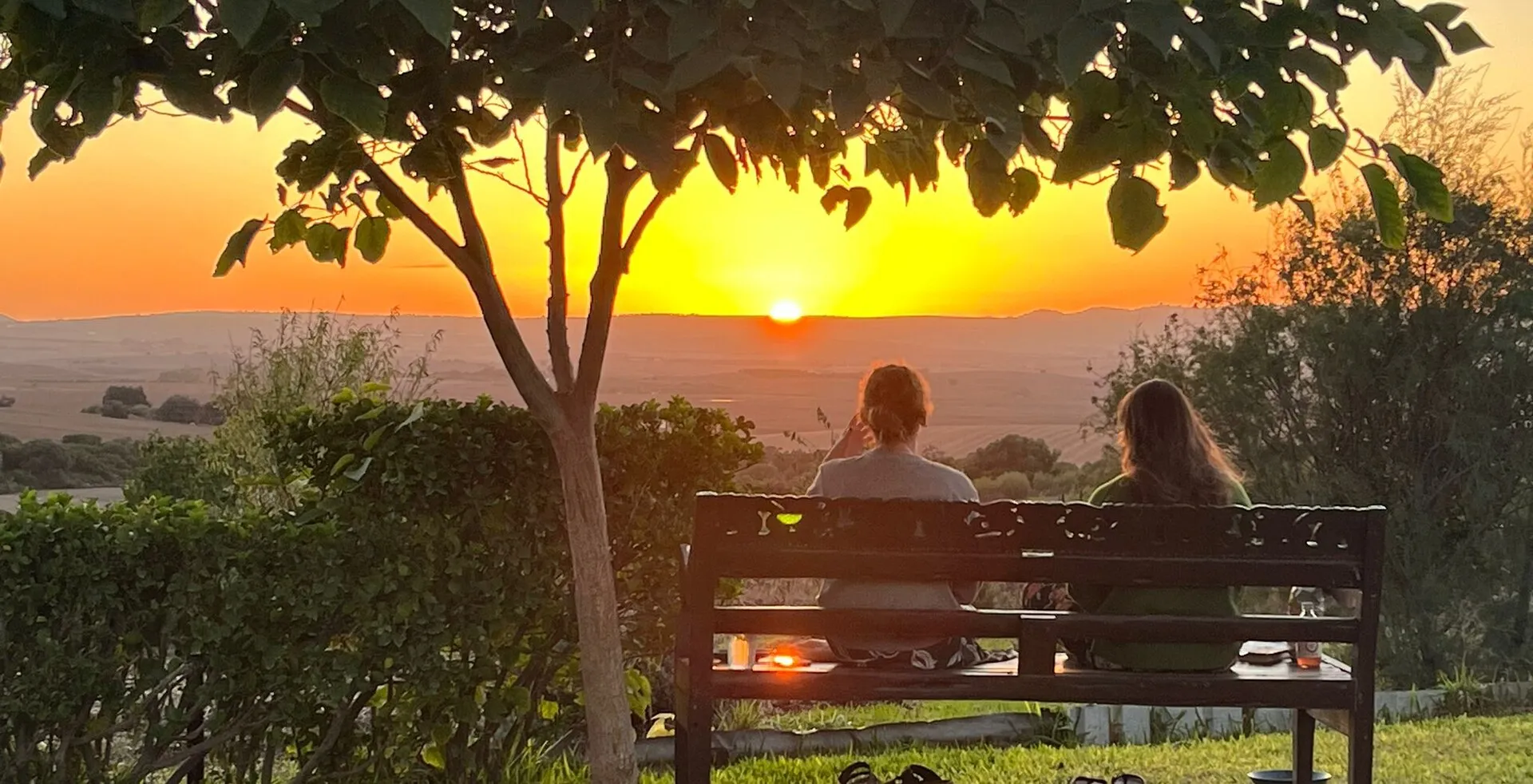 Two people on a bench watching the sun set over the Andalusian countryside at Suryalila